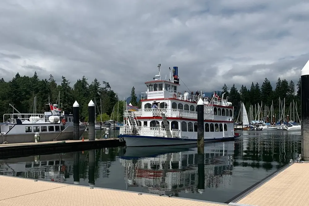 A white Harbour Cruises boat docked with forested hills behind.