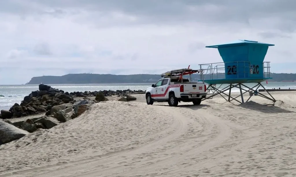 A lifeguard truck and tower sit on the sandy shore of Coronado Beach, California.