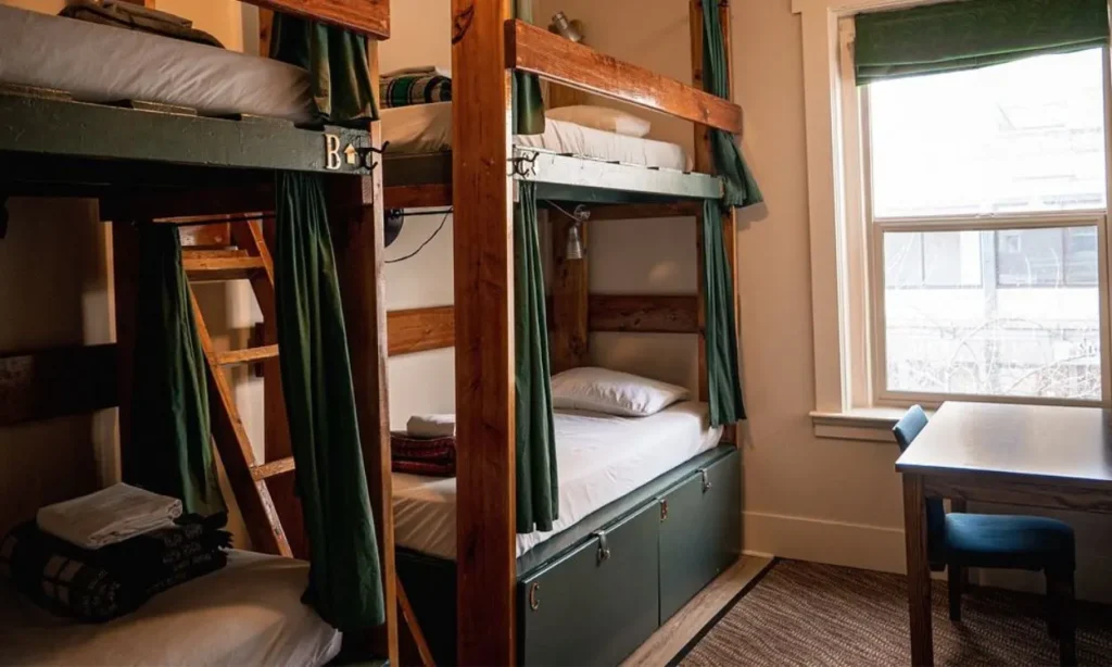 Bunk bed room with wooden frames, green curtains, and a windowed desk area.