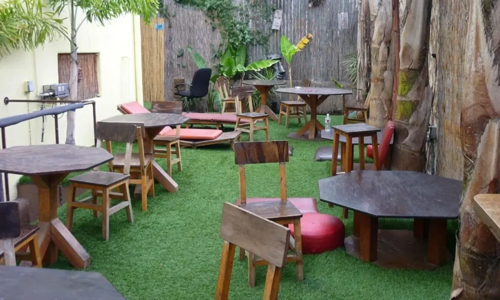 An outdoor patio at Banana Bungalow Hollywood with wooden tables, chairs, and greenery.