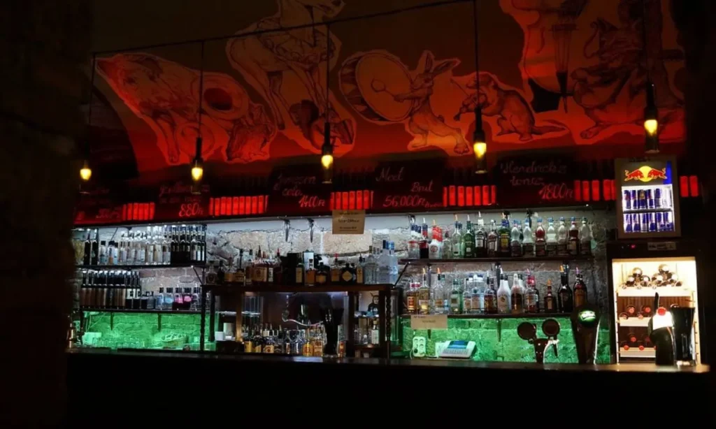 A lively bar with bottles and playful murals on the ceiling at Instant-Fogas.