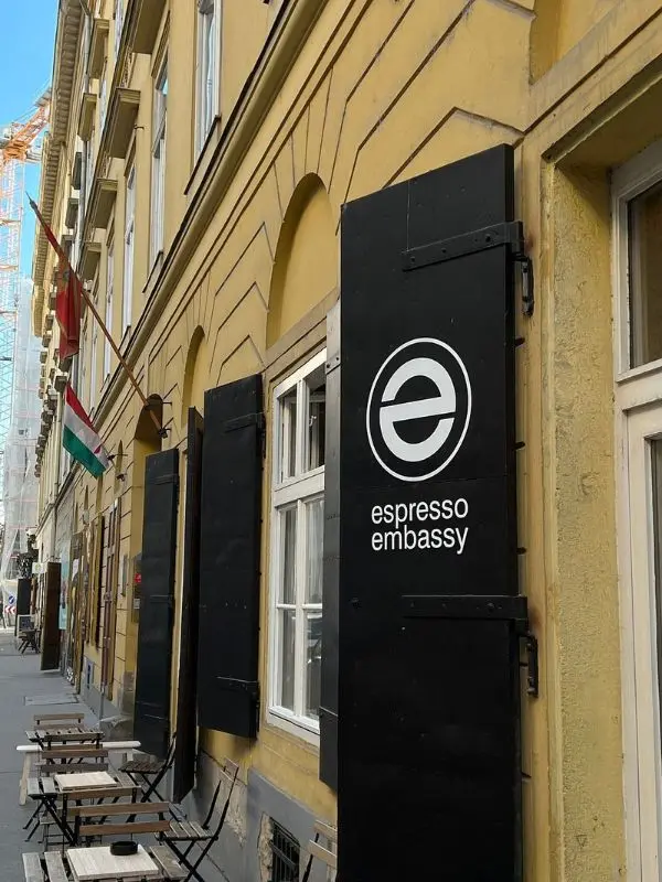 Outdoor seating in front of the Espresso Embassy café on a narrow street.