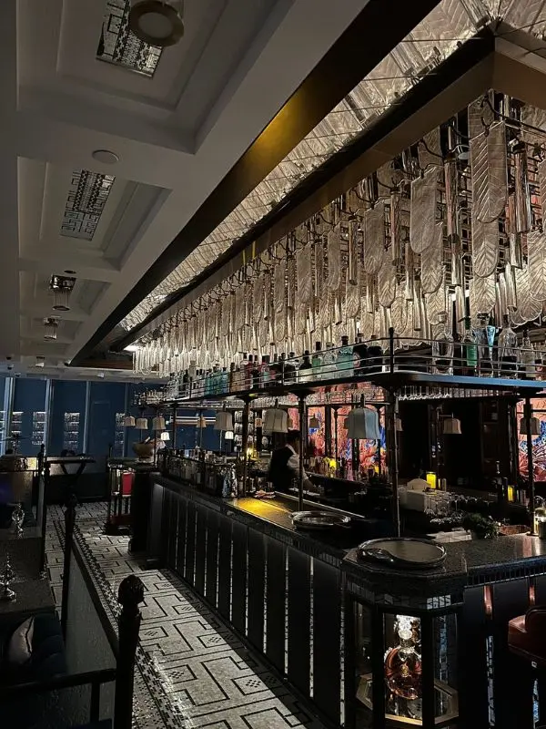 The elegant interior of At.mosphere restaurant with a decorative bar and hanging glass details.