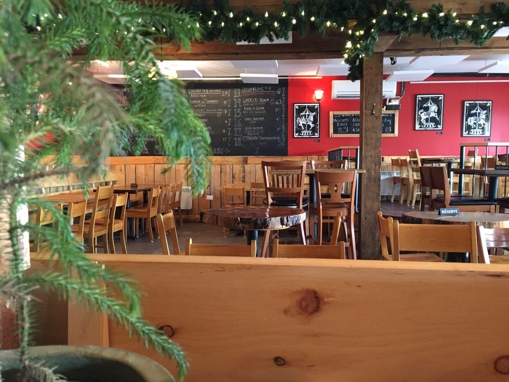 Cozy wooden interior of La Souche with red walls, chalkboard menu, and string lights.