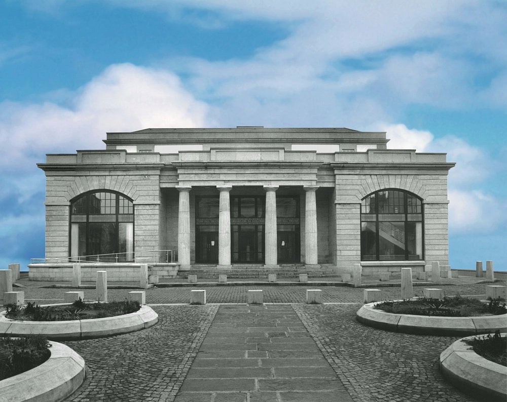 Front view of the Town Hall Theatre, a neoclassical stone building with tall columns and arched windows under a blue sky.