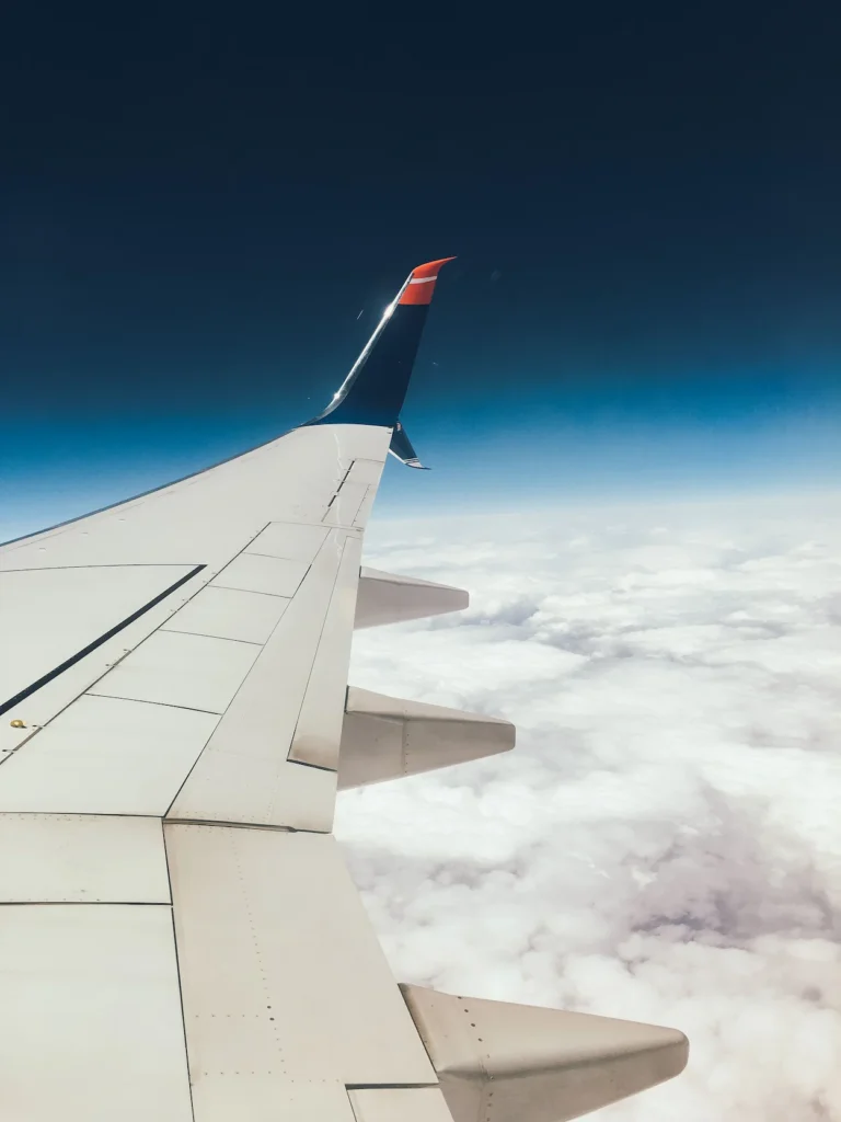 Airplane wing flying high above a thick layer of white clouds