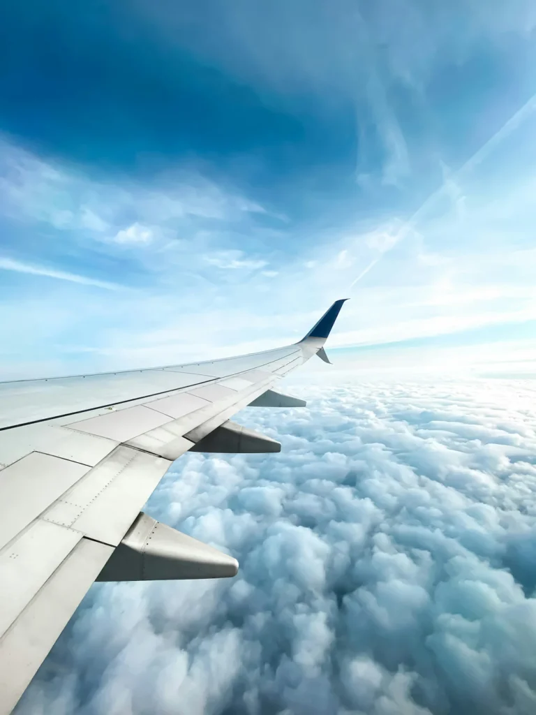 An airplane wing flying above a thick layer of white clouds
