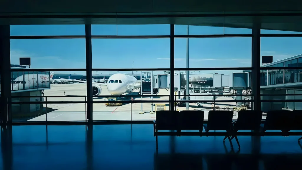 A parked airplane on the tarmac viewed through a large terminal gate window