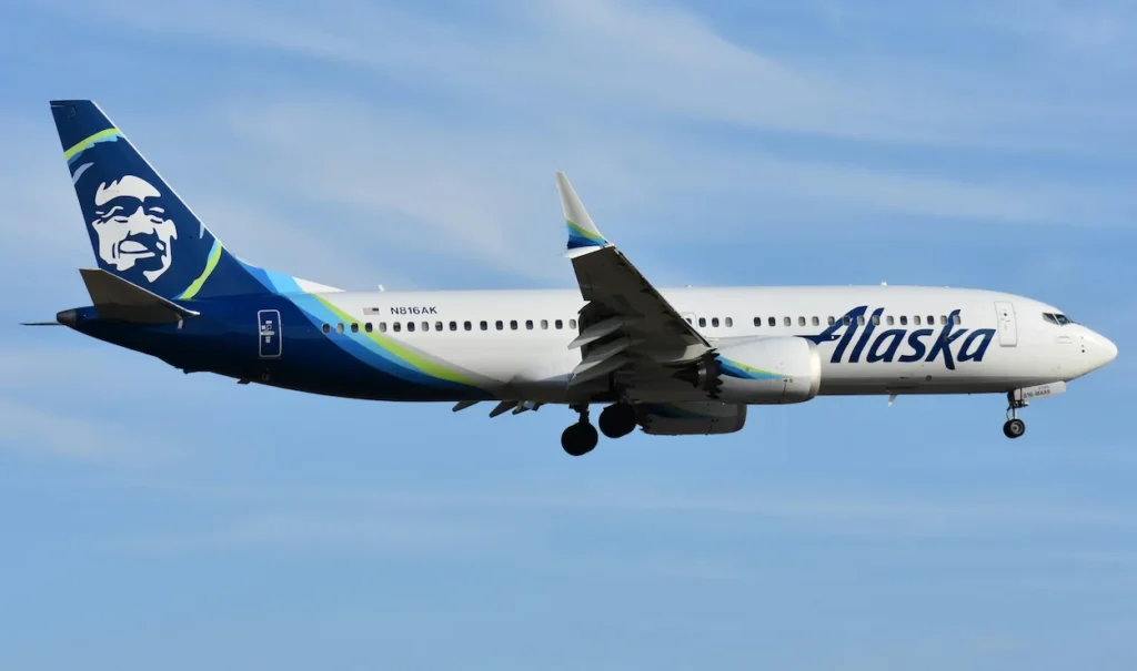 Alaska Airlines Boeing 737 MAX 9 aircraft on final approach with landing gear down against a hazy sky
