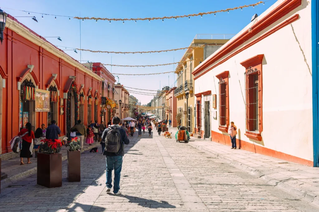 People walking down the cobblestone path of Andador Turistico Macedonio Alcala in Oaxaca Mexico