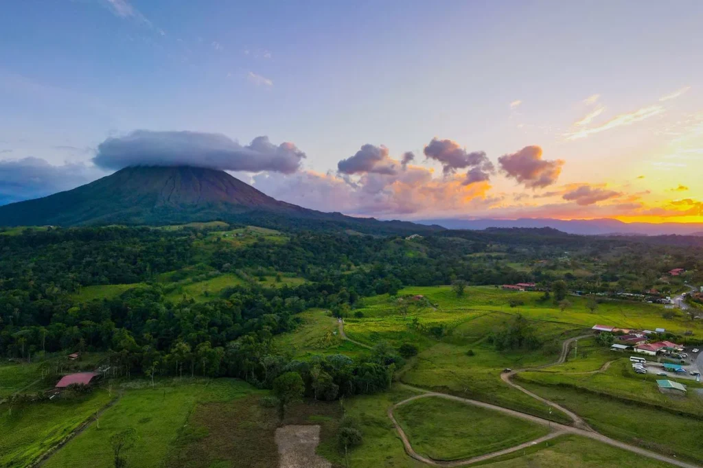 Arenal Volcano surrounded by green fields at sunset