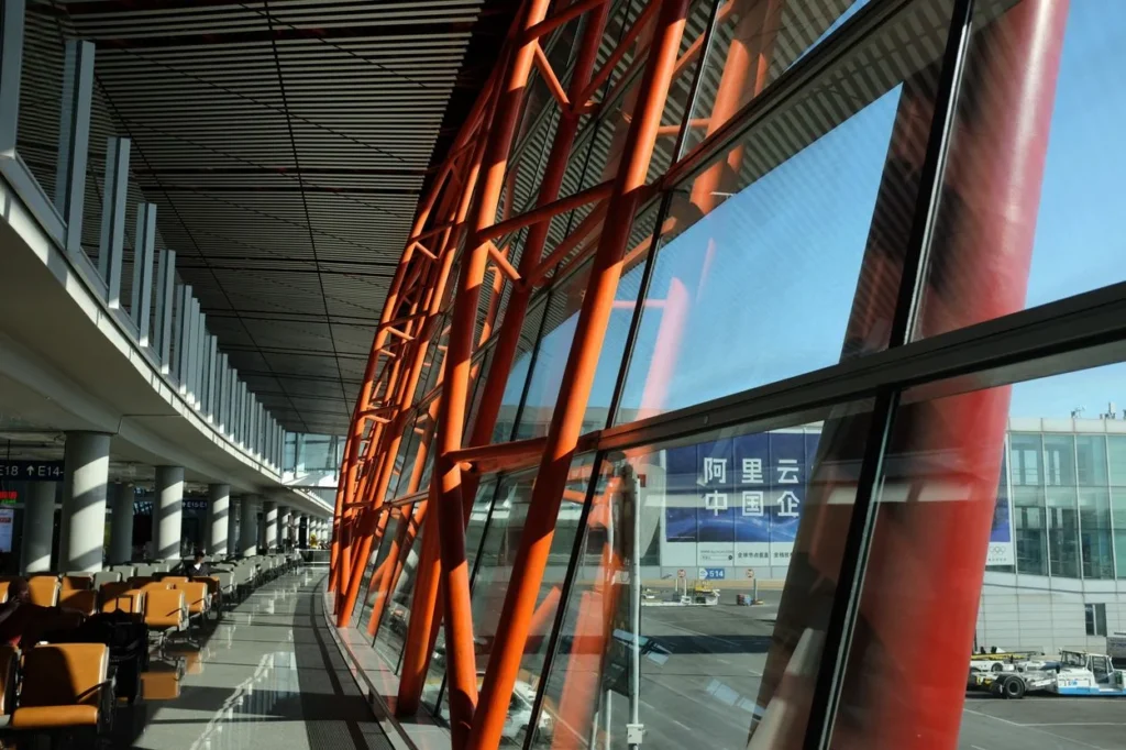 Red support structure and large glass windows inside Beijing Capital Airport Terminal 3