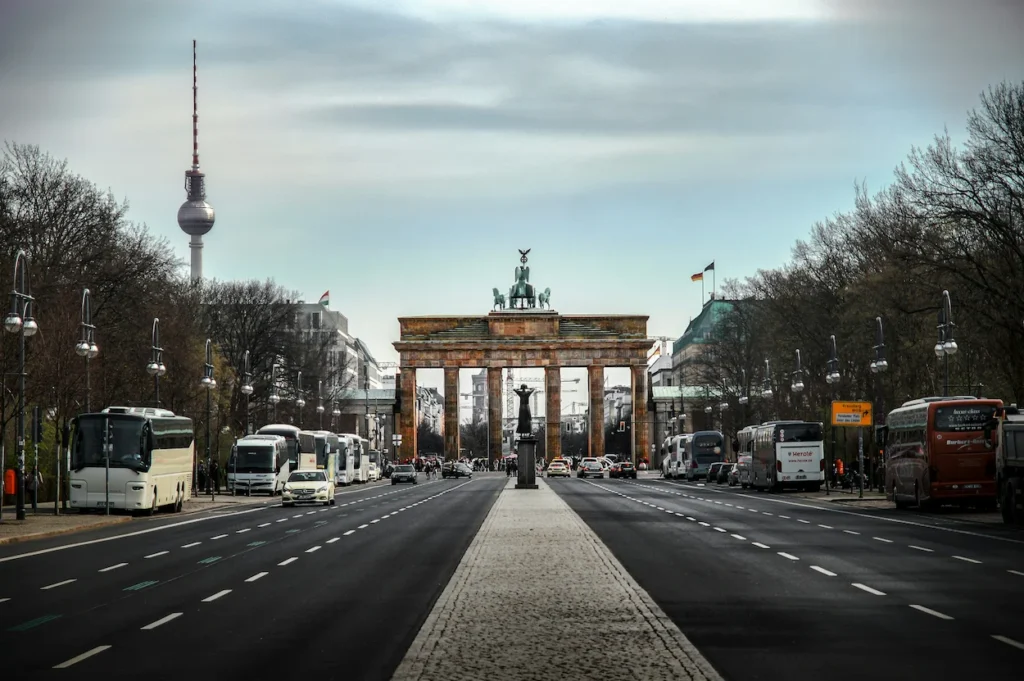 A wide road leading toward the historic Brandenburg Gate in Berlin with the TV Tower visible in the background