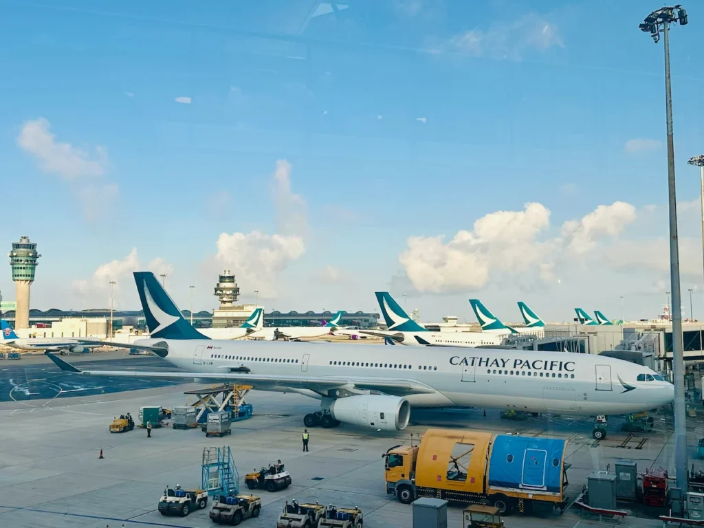 Cathay Pacific Airbus A330 parked at a busy airport terminal gate under a clear sky