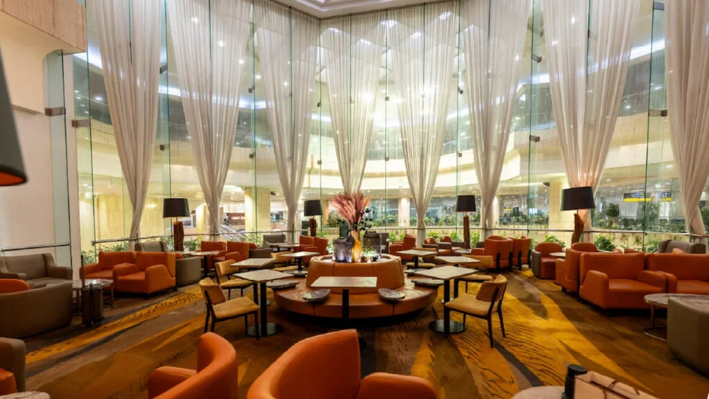 Plaza Premium Lounge at Dammam Airport featuring grand white drapery and orange armchairs