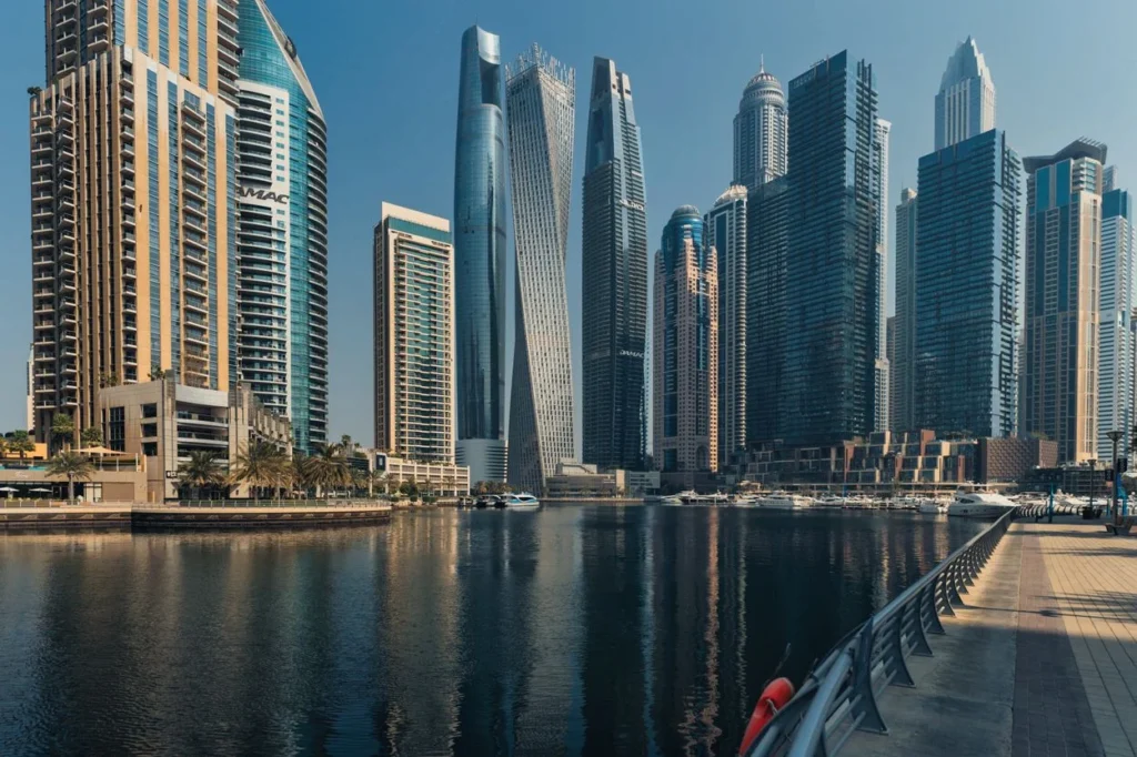 Towering skyscrapers including the twisted Cayan Tower reflecting on the water at Dubai Marina