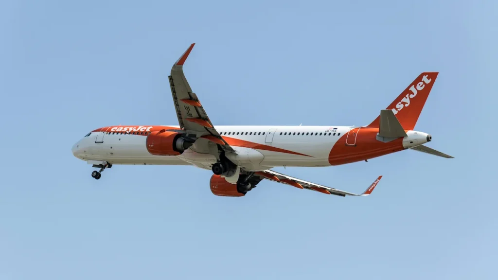 easyJet Airbus A321neo airplane flying overhead with landing gear down