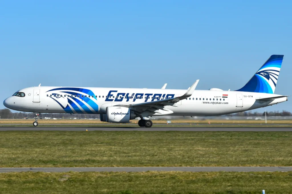 An EgyptAir Airbus A321neo taxiing on the airport runway against a clear blue sky