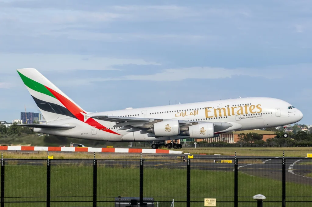 Emirates Airbus A380 double-decker commercial airplane touching down on an airport runway