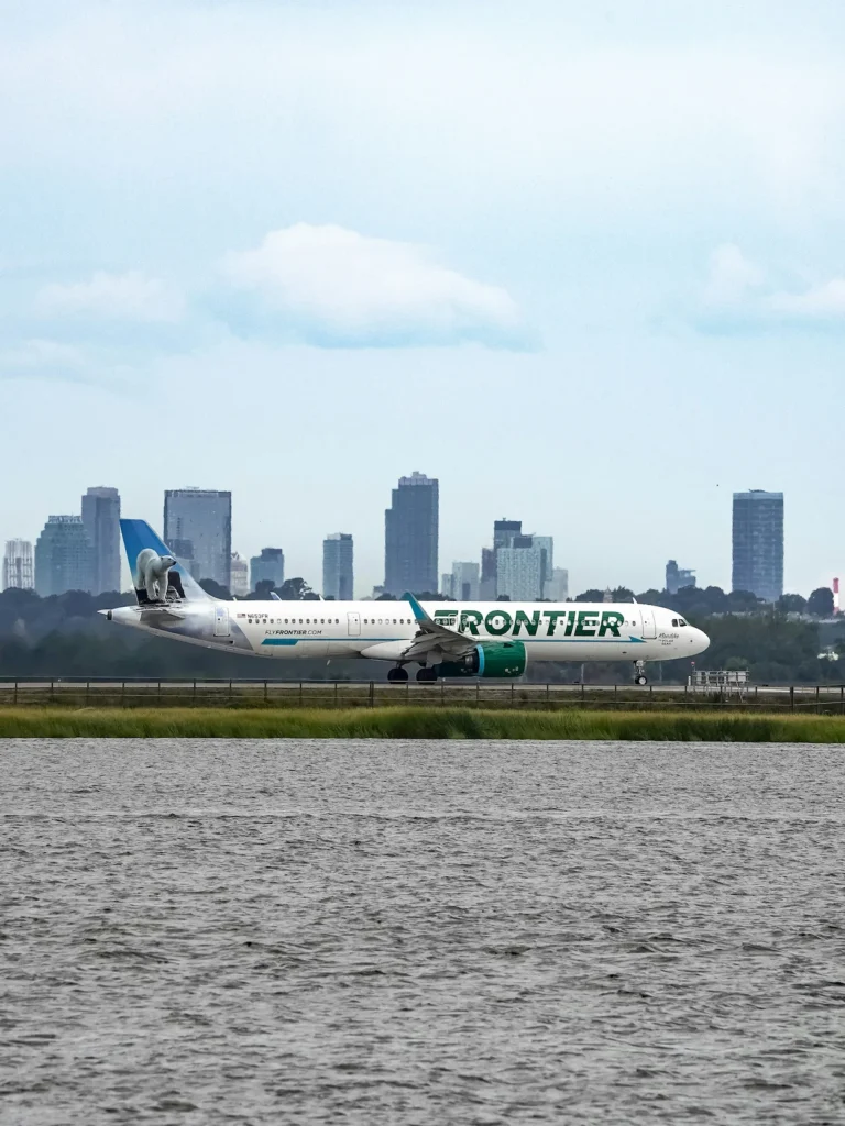 A Frontier Airlines Airbus A321neo airplane with a polar bear tail design taxiing near a city
