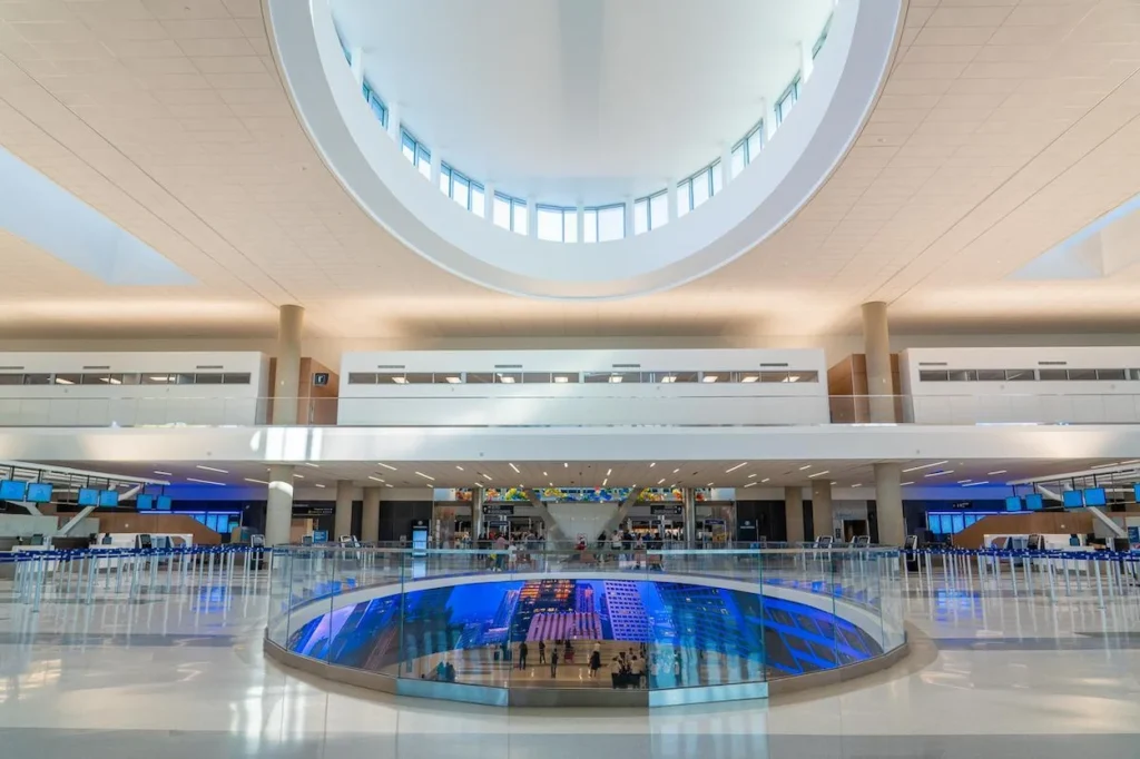 A multi-level airport atrium with a large circular lightwell and glass railing
