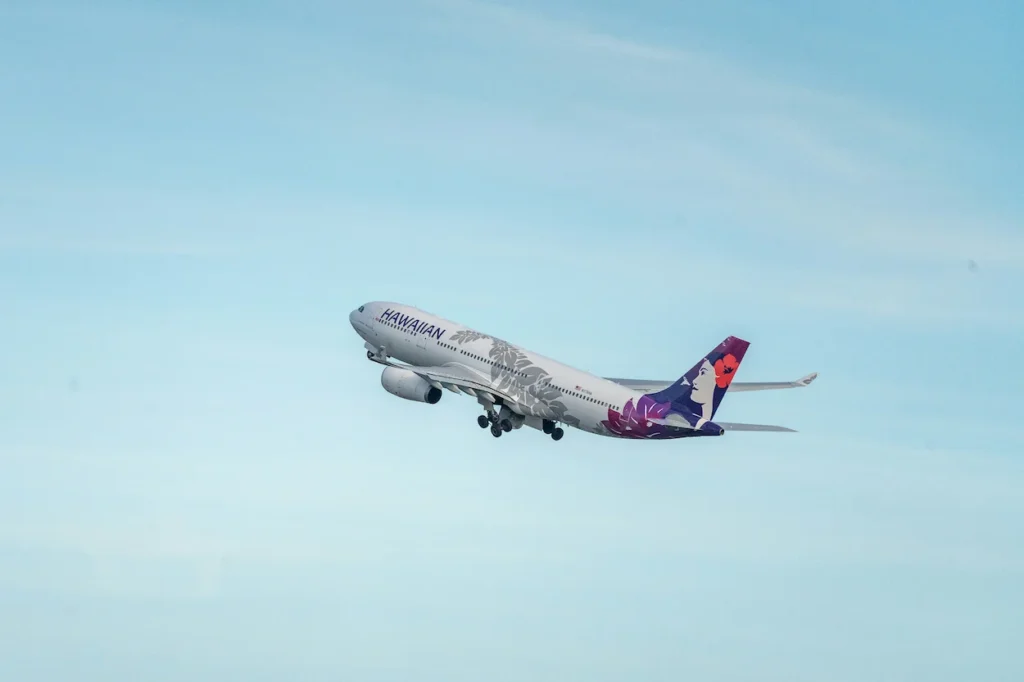 Hawaiian Airlines Airbus A330 widebody aircraft climbing into a light blue sky during takeoff