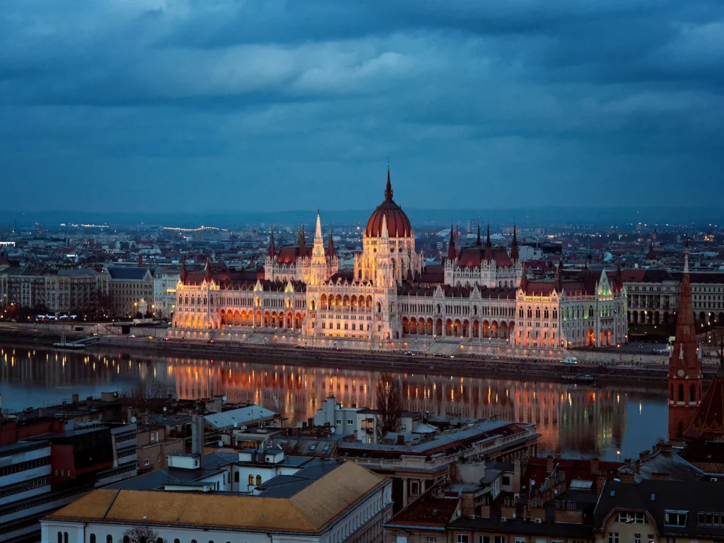 Illuminated Hungarian Parliament Building reflecting in the Danube River at dusk
