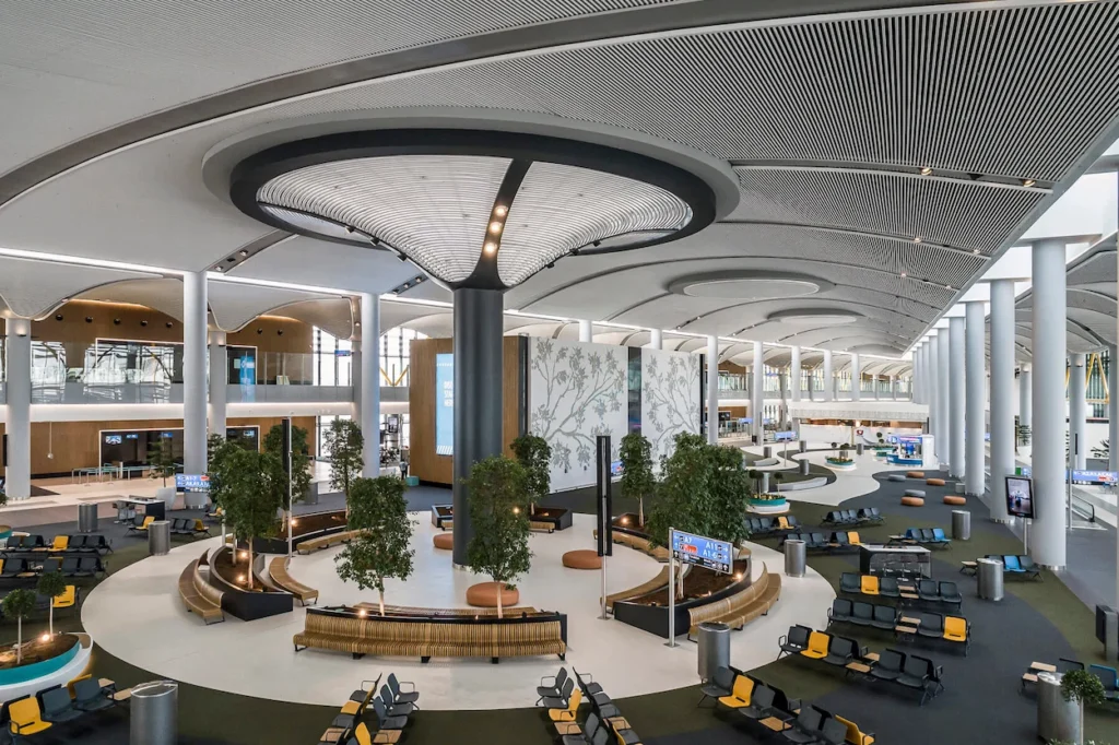Modern, tree-lined indoor plaza and circular seating areas inside Istanbul Airport