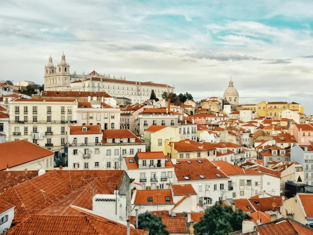 High-angle view of the Alfama district in Lisbon featuring terracotta rooftops and historic churches