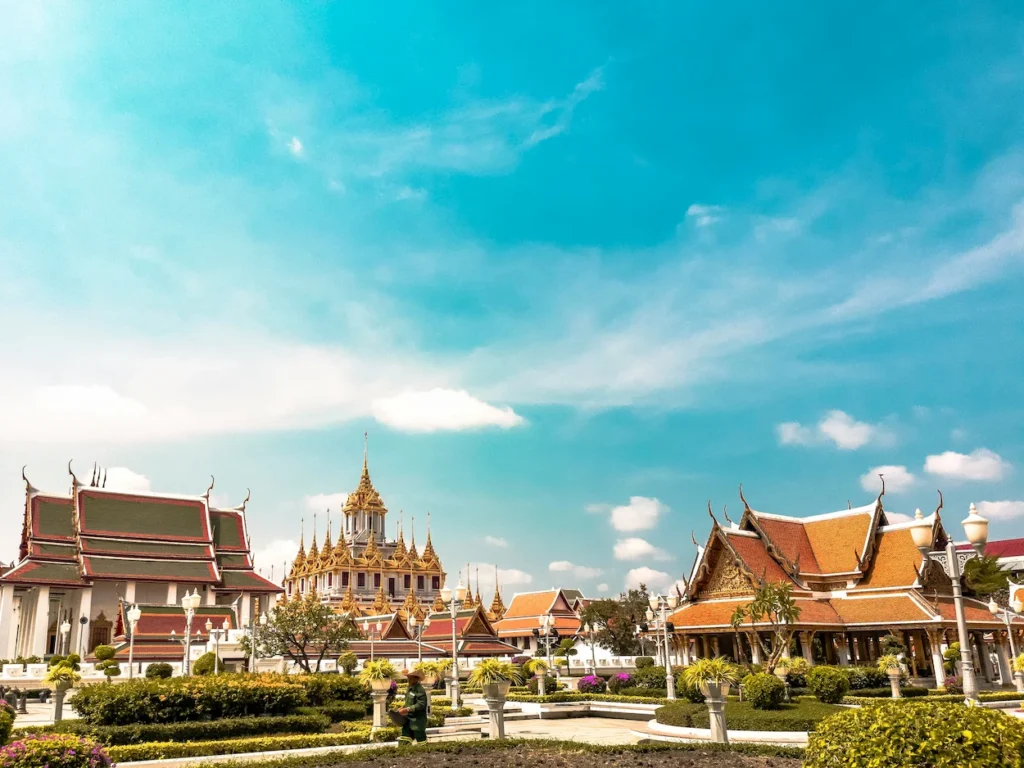 The golden spires of Loha Prasat temple surrounded by traditional Thai pavilions under a blue sky