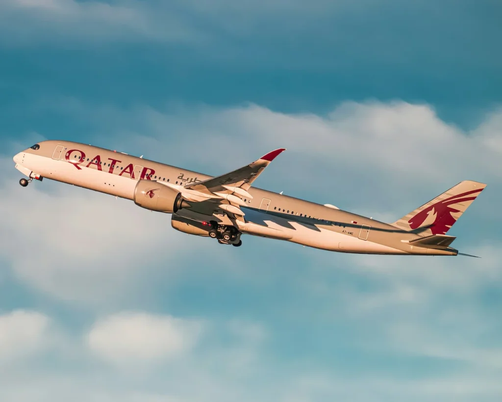 A Qatar Airways Airbus A350-1000 climbing steeply into the sky after takeoff
