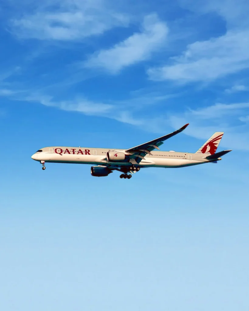 Qatar Airways Airbus A350 passenger airplane descending for a landing against a bright blue sky