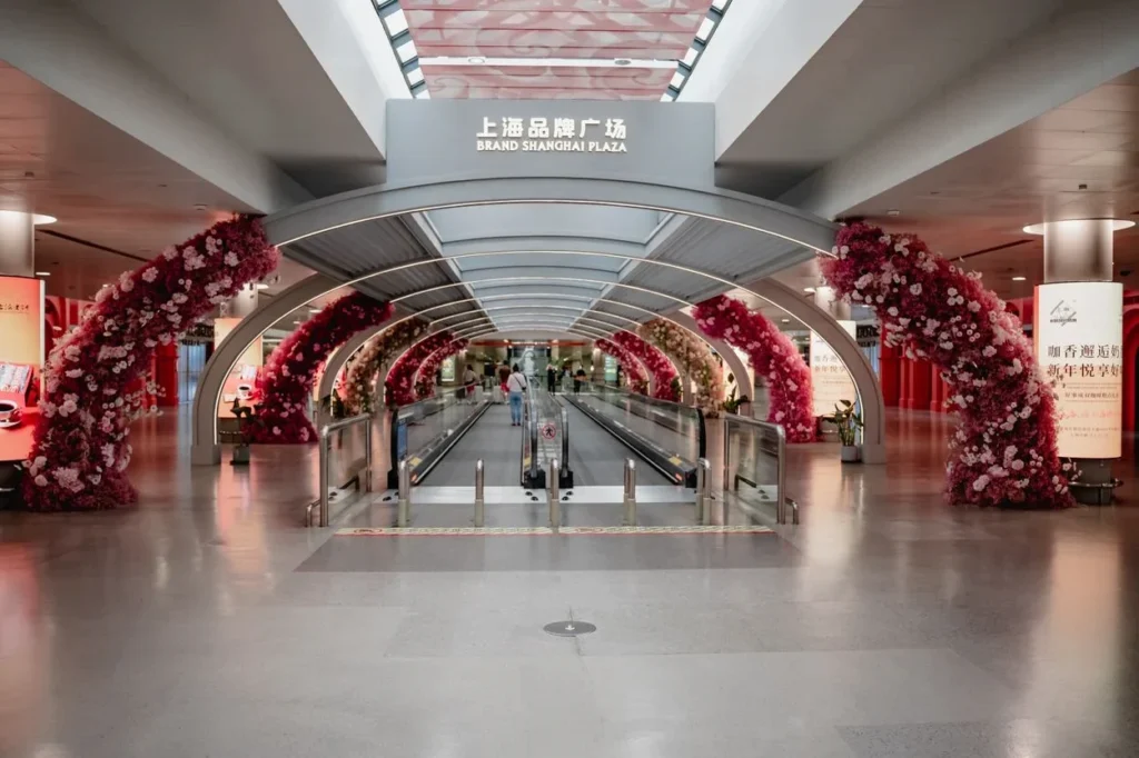 A moving walkway framed by pink flower arches at Brand Shanghai Plaza