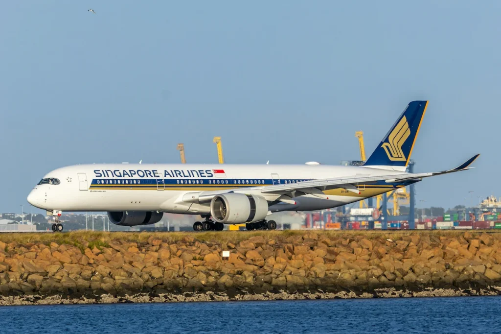 Singapore Airlines Airbus A350 passenger airliner taxiing past a coastal stone wall