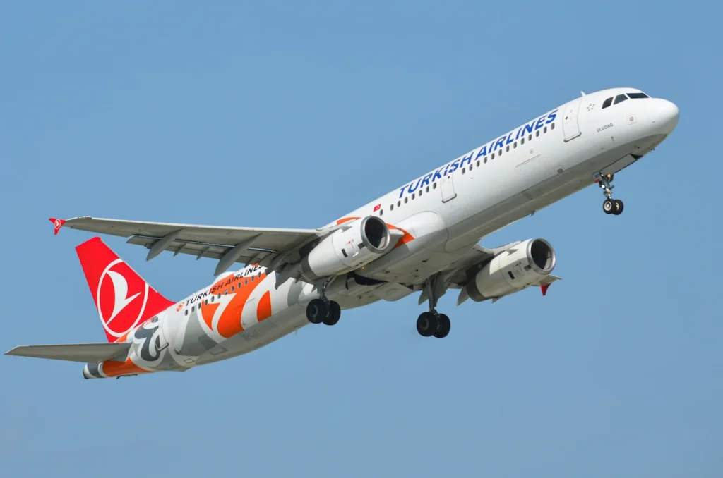 Turkish Airlines Airbus A321 passenger airplane with retro livery banking upward into a clear blue sky