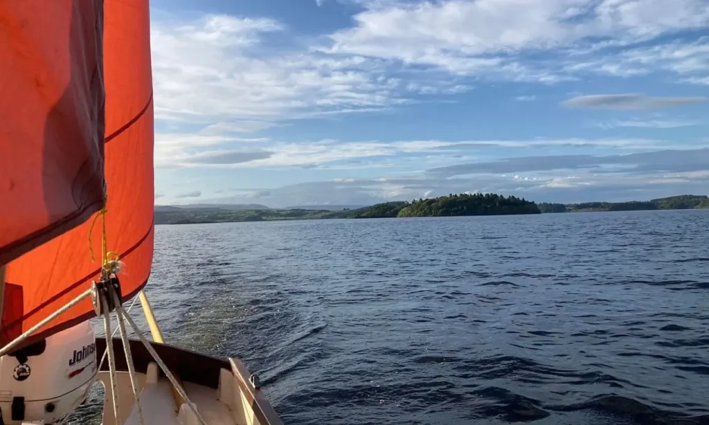 A sailboat glides across the calm waters of Lough Corrib.