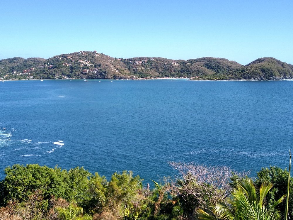 View of Bahía de Zihuatanejo with blue water and green hills in the background.