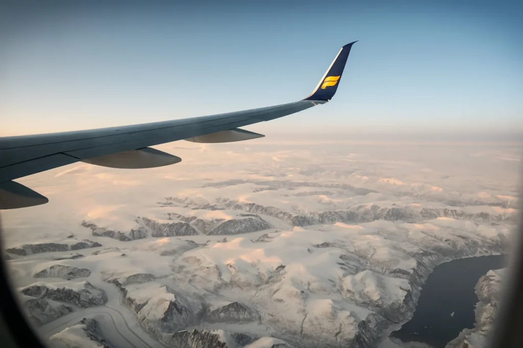 Icelandair airplane winglet flying over snow-covered mountains and glaciers