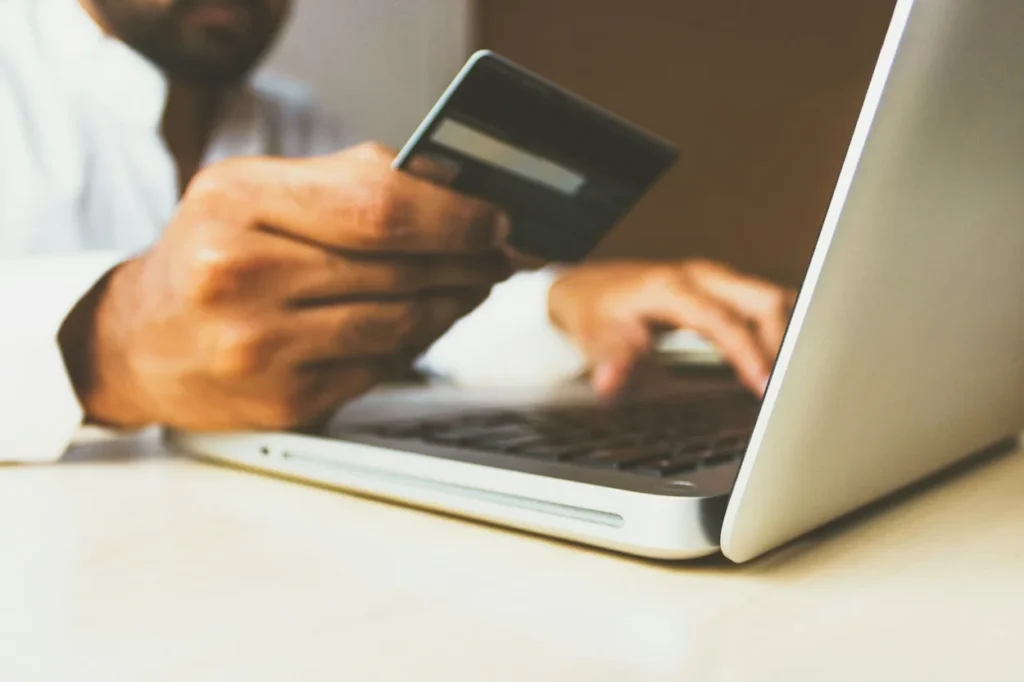 Person holding a credit card while typing on a laptop computer