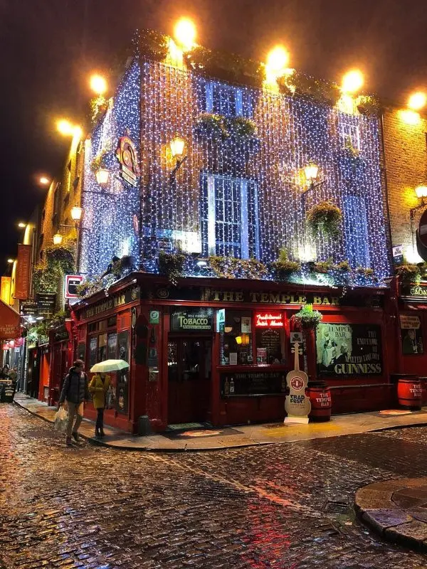 The Temple Bar Pub is decorated with glowing lights on a rainy night.