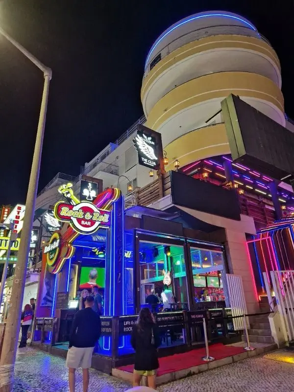 The neon-lit Rock & Roll Bar stands out on the lively Strip in Albufeira at night.