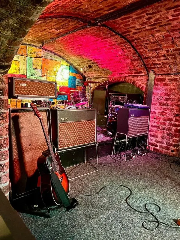 The Cavern Club’s small brick stage is set with guitars and amplifiers.