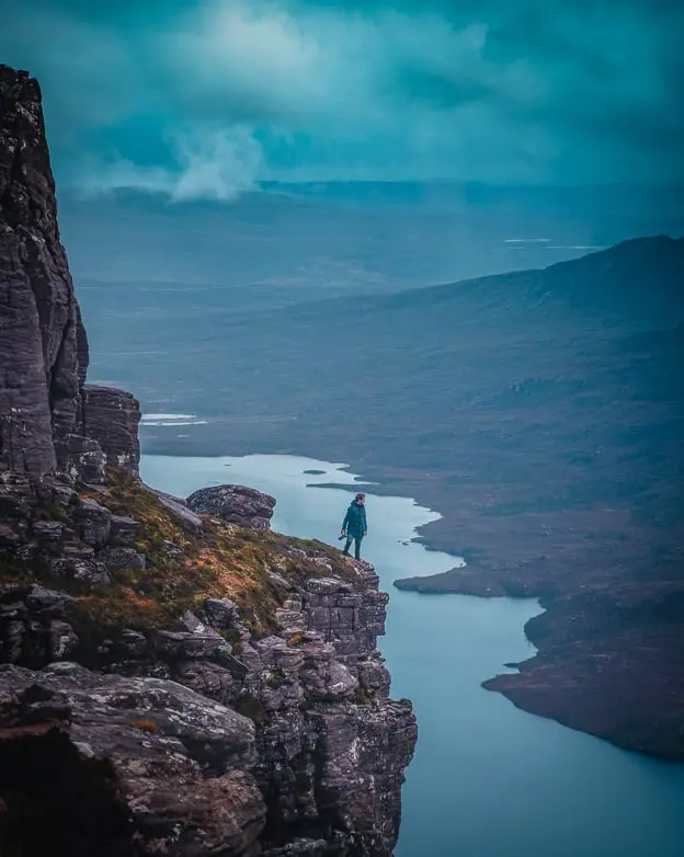 A person standing on a cliff on a high mountain