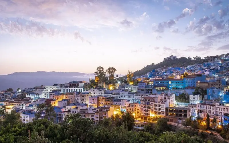 Colorful hillside buildings at sunset in Chefchaouen, Morocco.