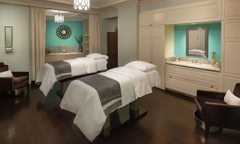 A calm double spa room with warm lighting and neutral tones at Waldorf Astoria Atlanta Buckhead.