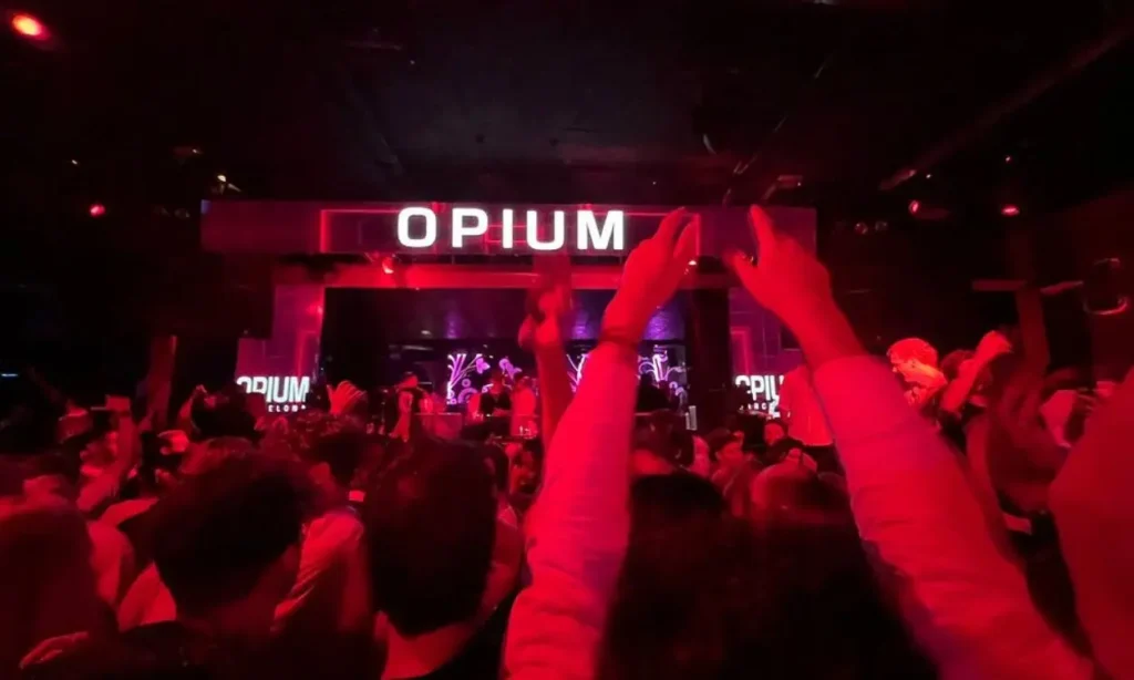 A packed dance floor under red lights at Opium nightclub in Barcelona.