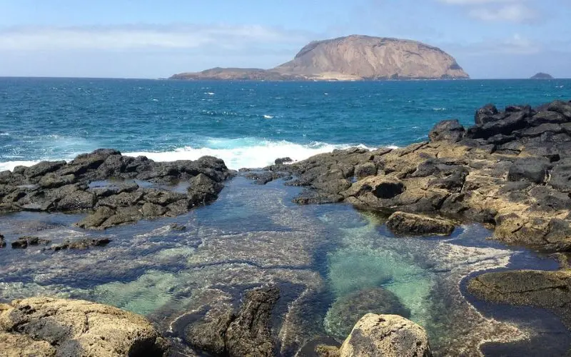 Rocky shore with ocean waves and island views in the Canary Islands.