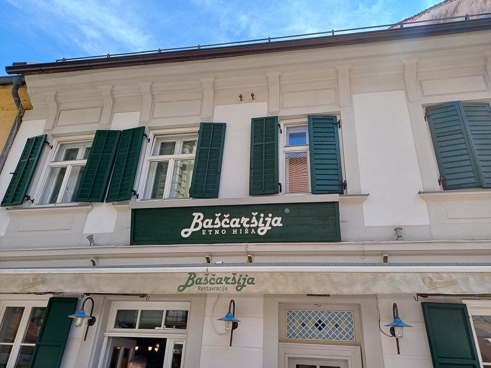 Exterior of Baščaršija Maribor restaurant with green shutters and sign.
