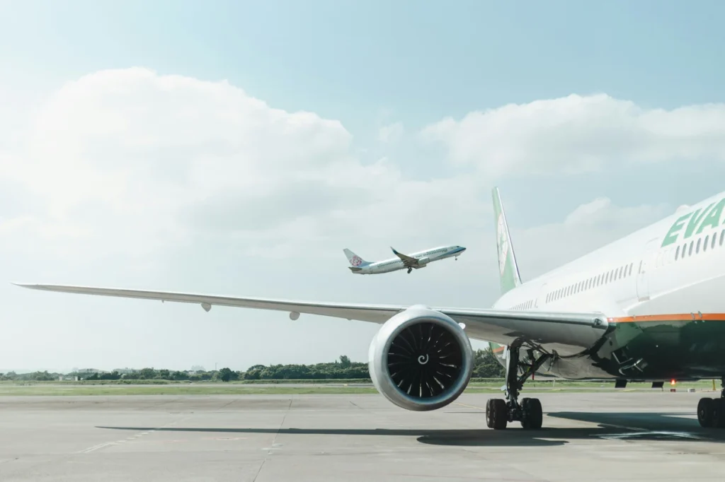 EVA Air 777 on the tarmac at Taipei with a China Airlines aircraft taking off behind
