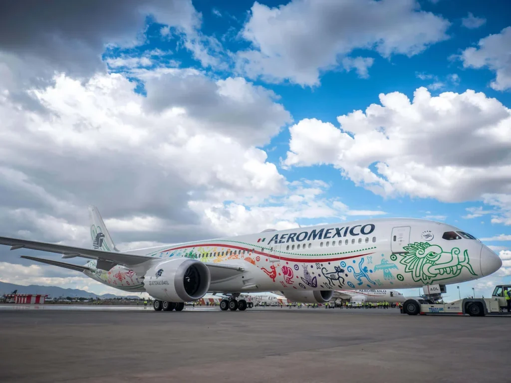 An Aeroméxico Boeing 787 with colorful Quetzalcoatl artwork parked on an airport tarmac